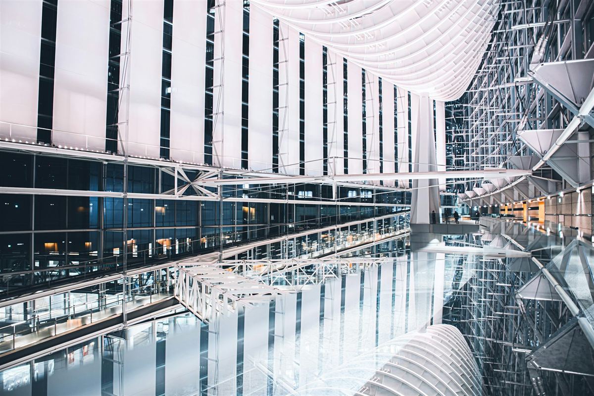 A glass atrium seen along its length at night, its lit steelwork reflected in the floor