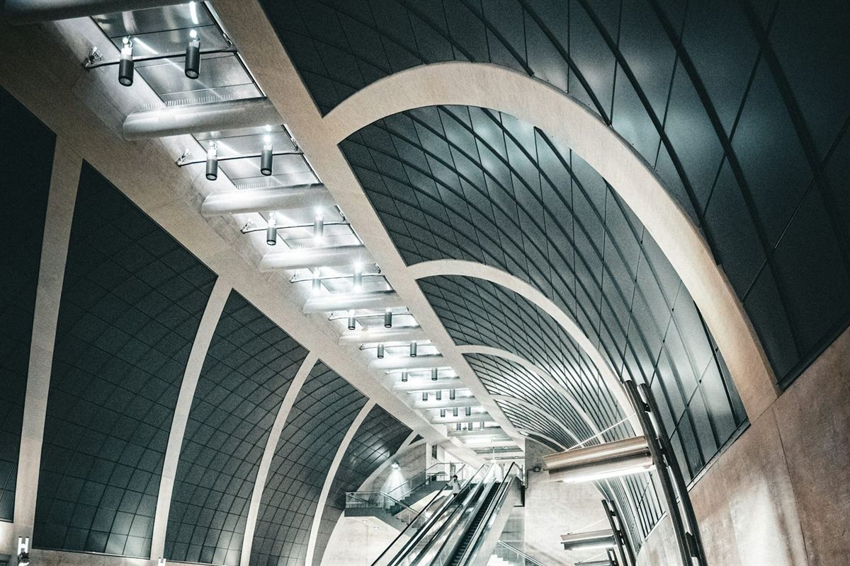 A vaulted, ribbed ceiling arching over an escalator