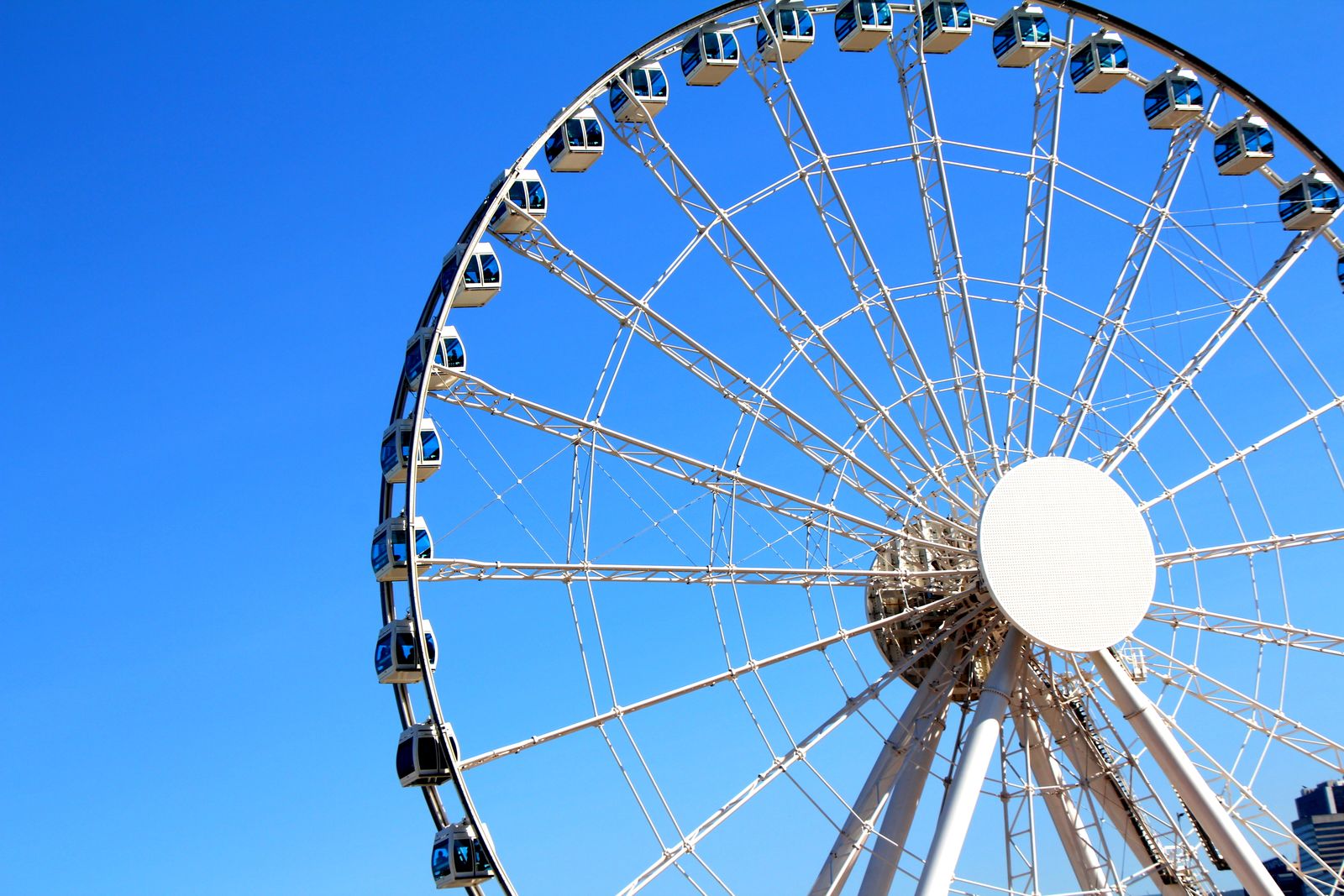 An observation wheel against a bright blue sky