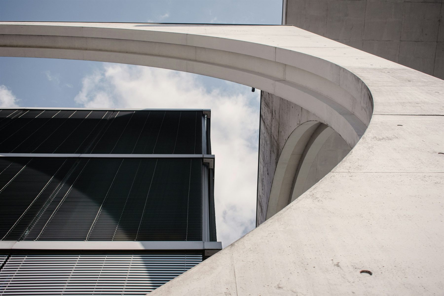 The curved concrete edge of a modern building meeting a glass facade