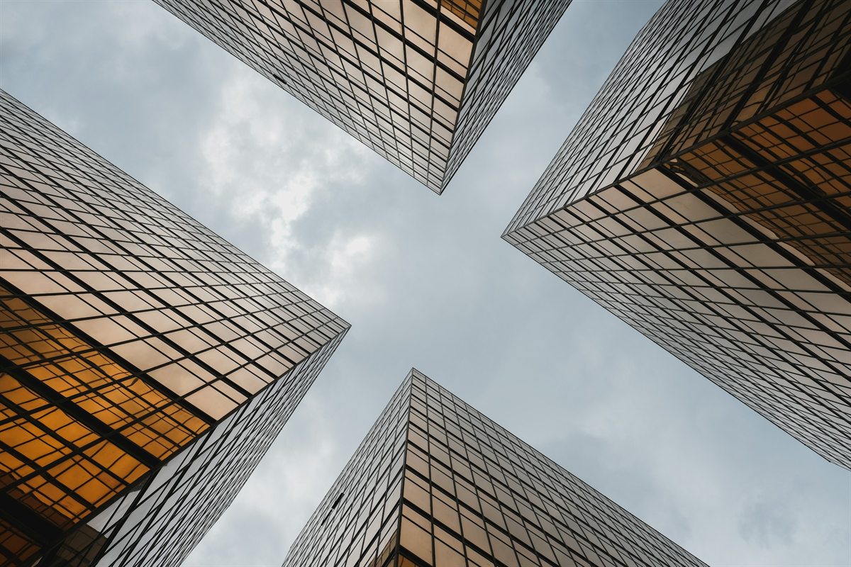 Gold-glass towers converging overhead against a pale sky